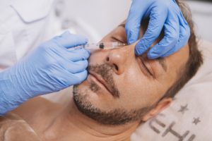 Doctor applying nose injectables to male patient's nose